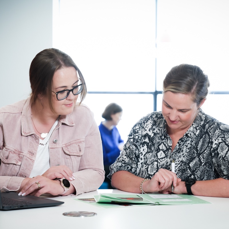 Two people working at a desk reading a worksheet