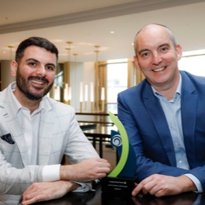 Two people posing with an award smiling