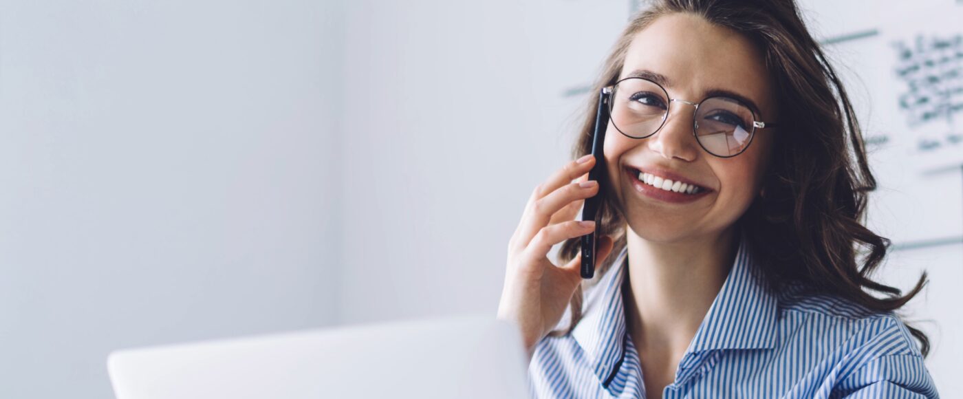 Woman smiling working on laptop and talking on phone