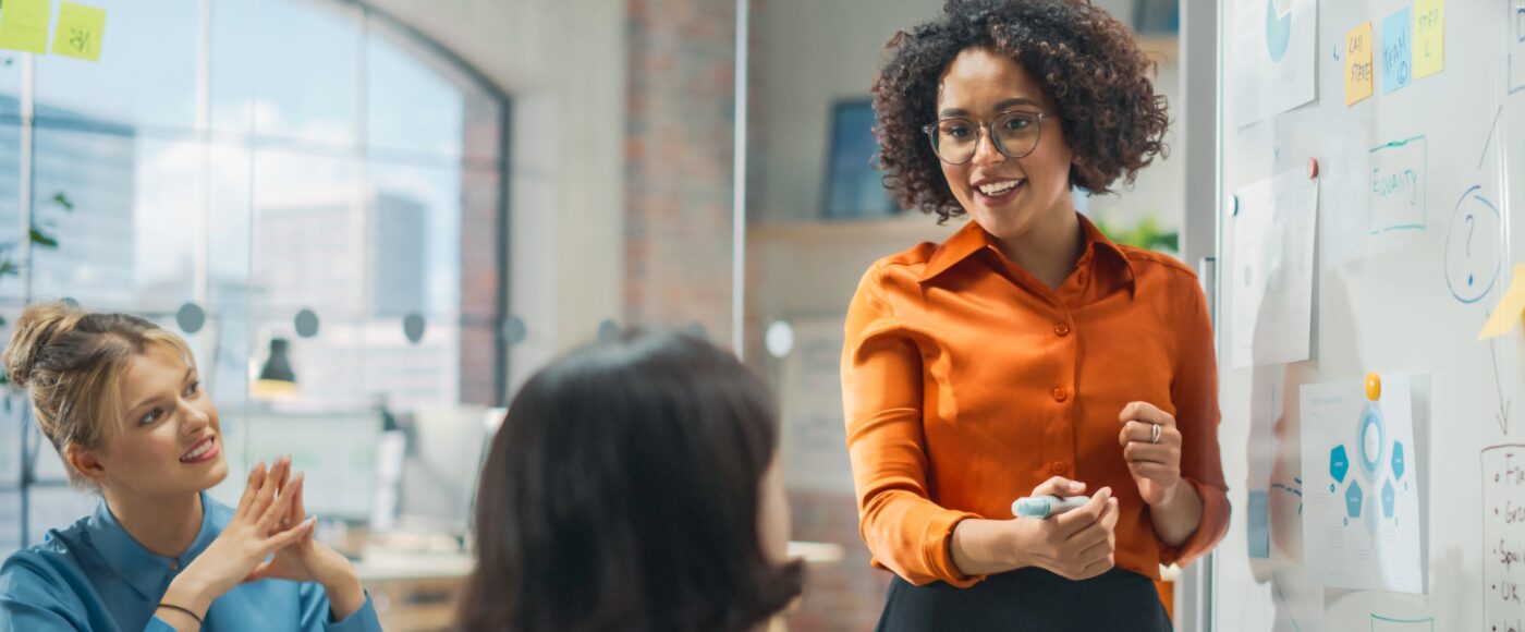Smiling office worker exploring ideas on a whiteboard infront of a group