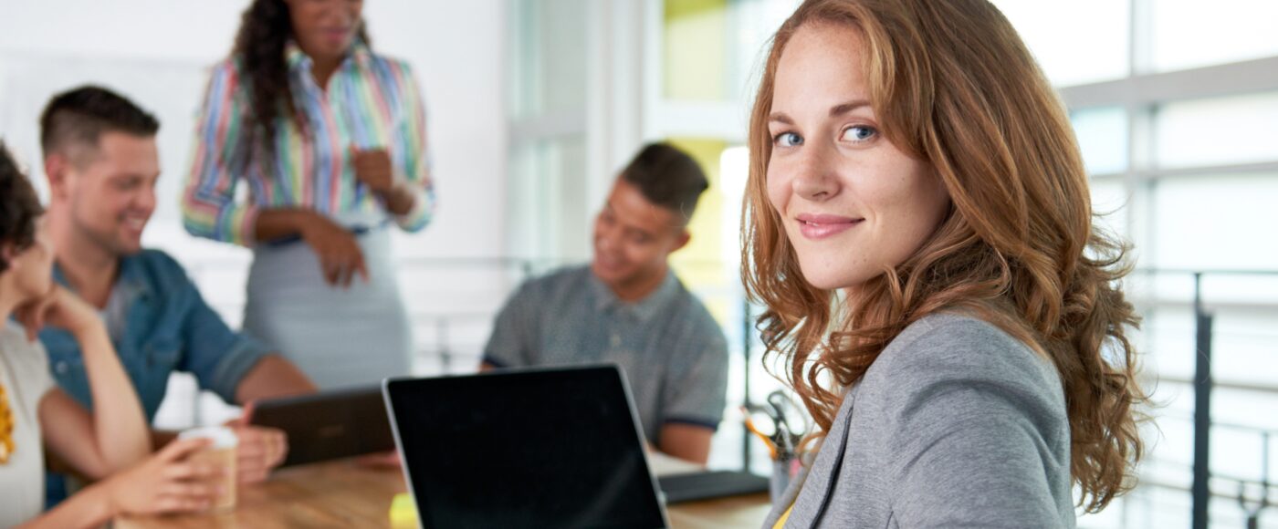 Professional seated with a laptop during a team meeting.